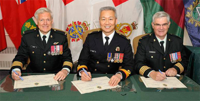 Le brigadier-général (à la retraite) Victor Lanctis, le commodore Hans Jung et le colonel (à la retraite) John Currah signent le certificat de changement d'affectation.
